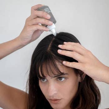 model applies the scalp detox treatment to their scalp