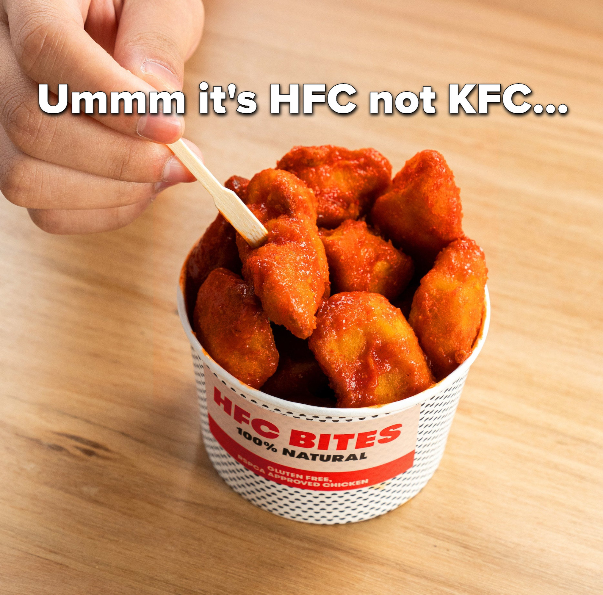 Pieces of chicken in a small container with the label &quot;HFC Bites — 100% natural&quot; and the caption &quot;Ummm it&#x27;s HFC not KFC&quot;