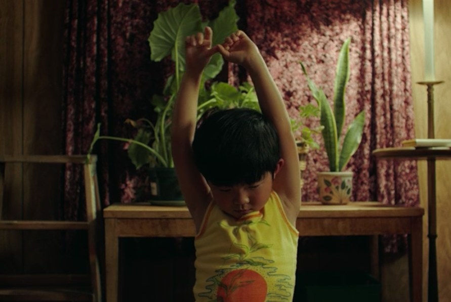 David looking at the living room floor while raising his two hands in the air.