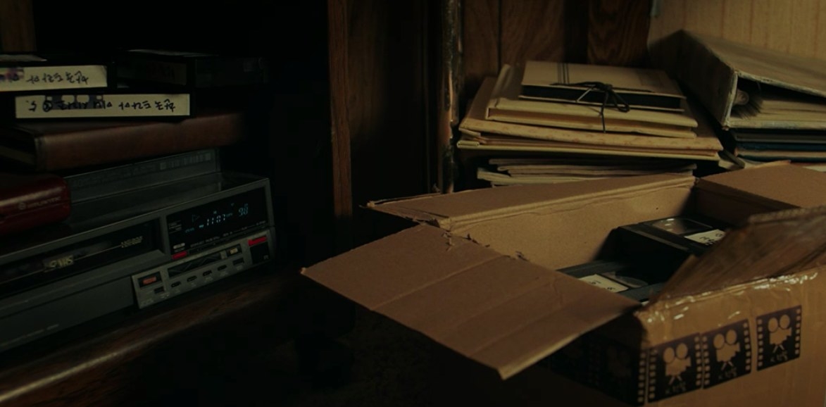 Messy stack of photo albums and VHS tapes on top of VHS player.