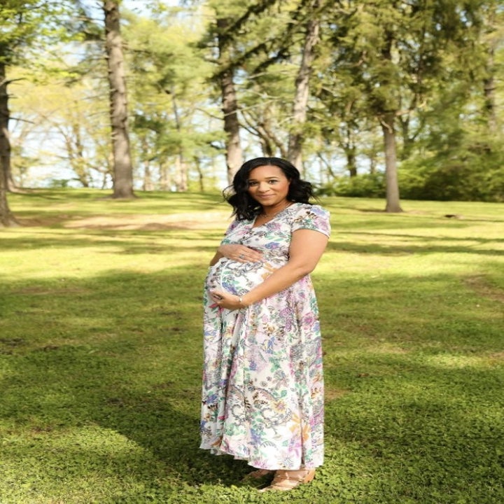 a reviewer wearing the white and colorful print dress while pregnant 