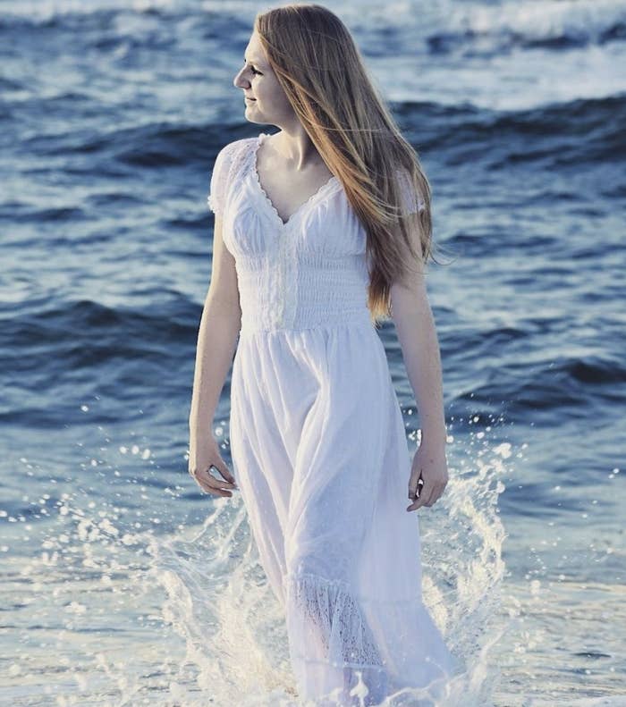A person is wearing a white peasant dress in the ocean