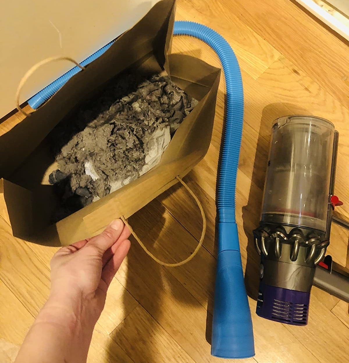 reviewer photo showing the vacuum attachment next to a bag full of the lint they suctioned out of their dryer 