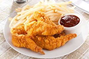 A plate of chicken tenders and fries with a side of bbq sauce 