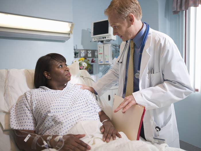 A Black, female patient being attended to by a white doctor