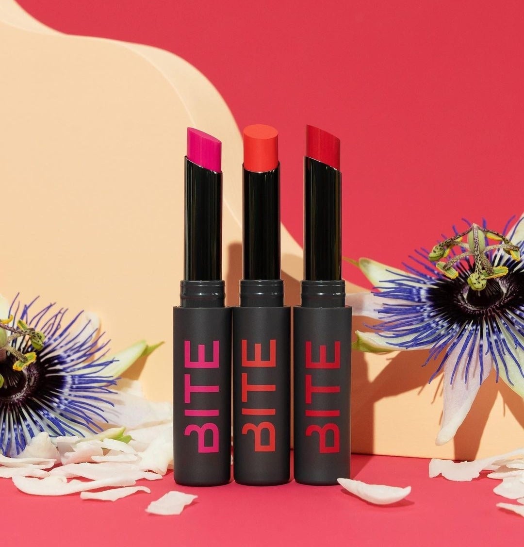 A trio of highly-pigmented lip sticks against a floral backdrop