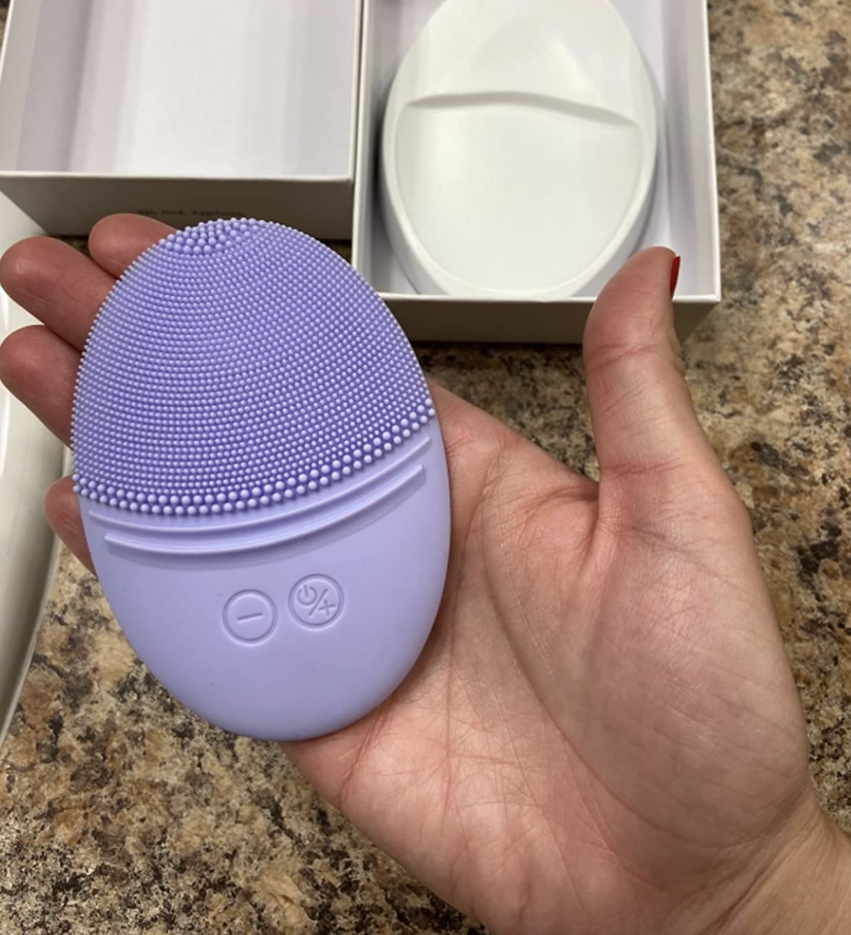A customer review photo of them holding the facial brush in purple