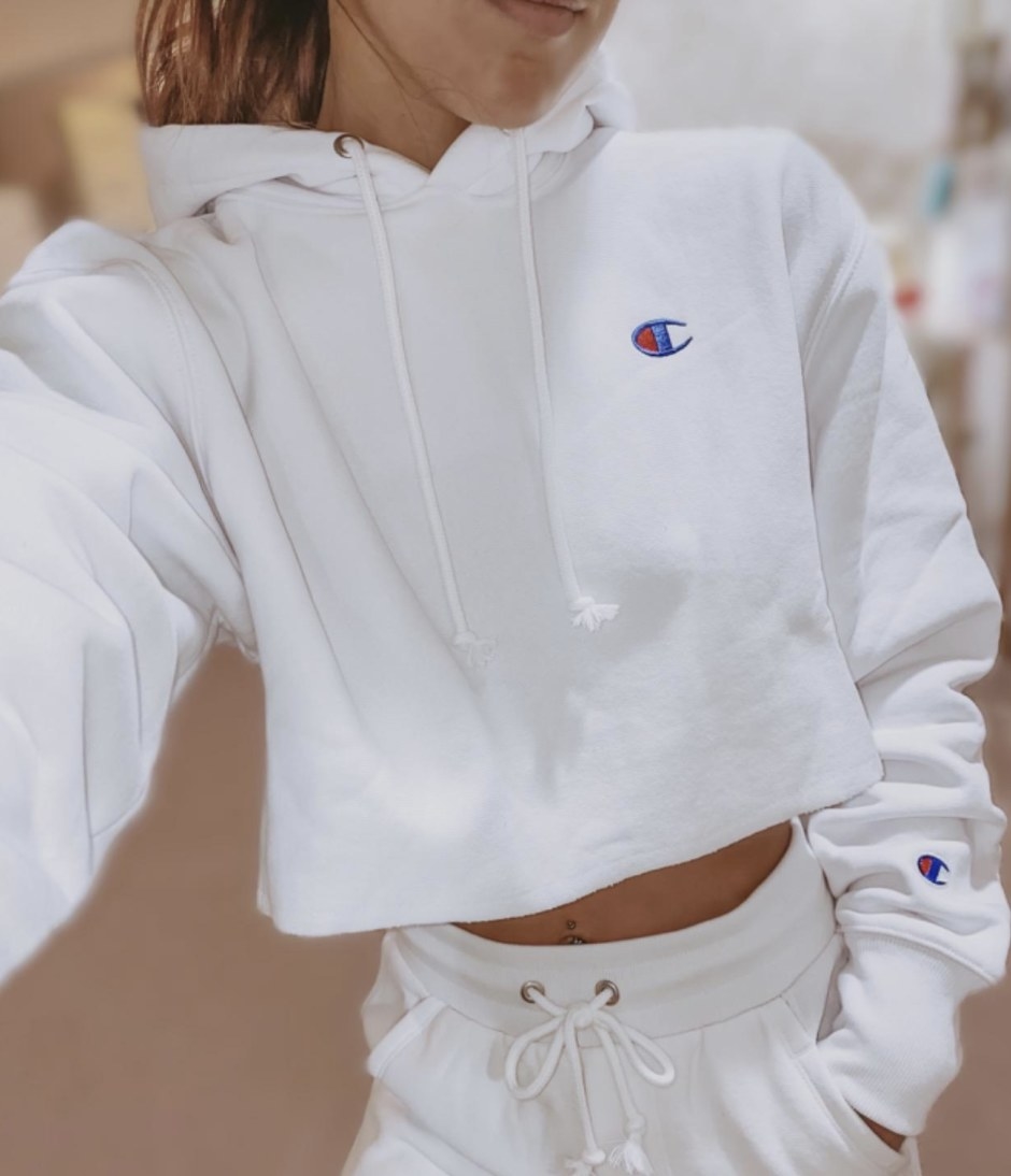 A person is wearing a white cropped hoodie and white shorts