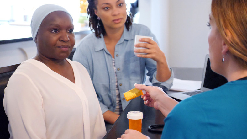 A Black, female patient receiving a prescription from a doctor