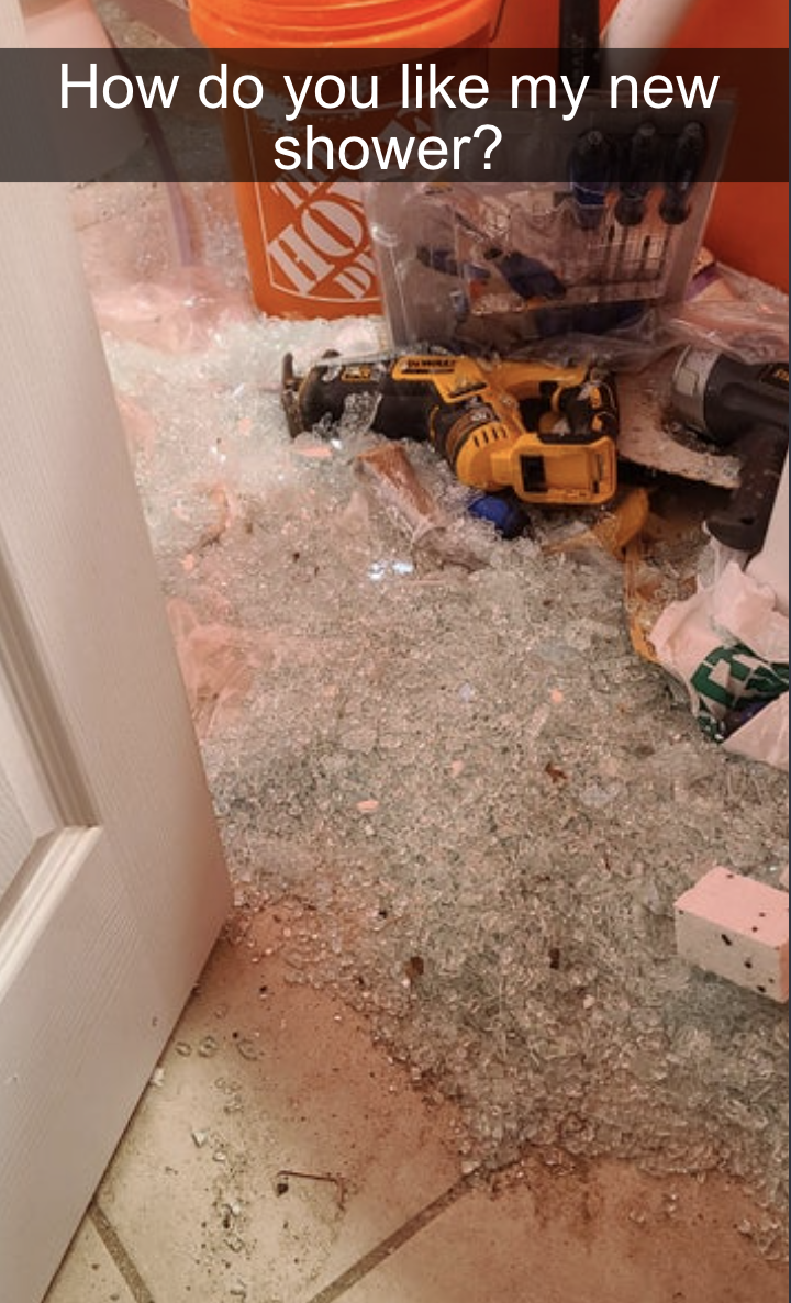 A shattered glass shower door in pieces all over the bathroom tile