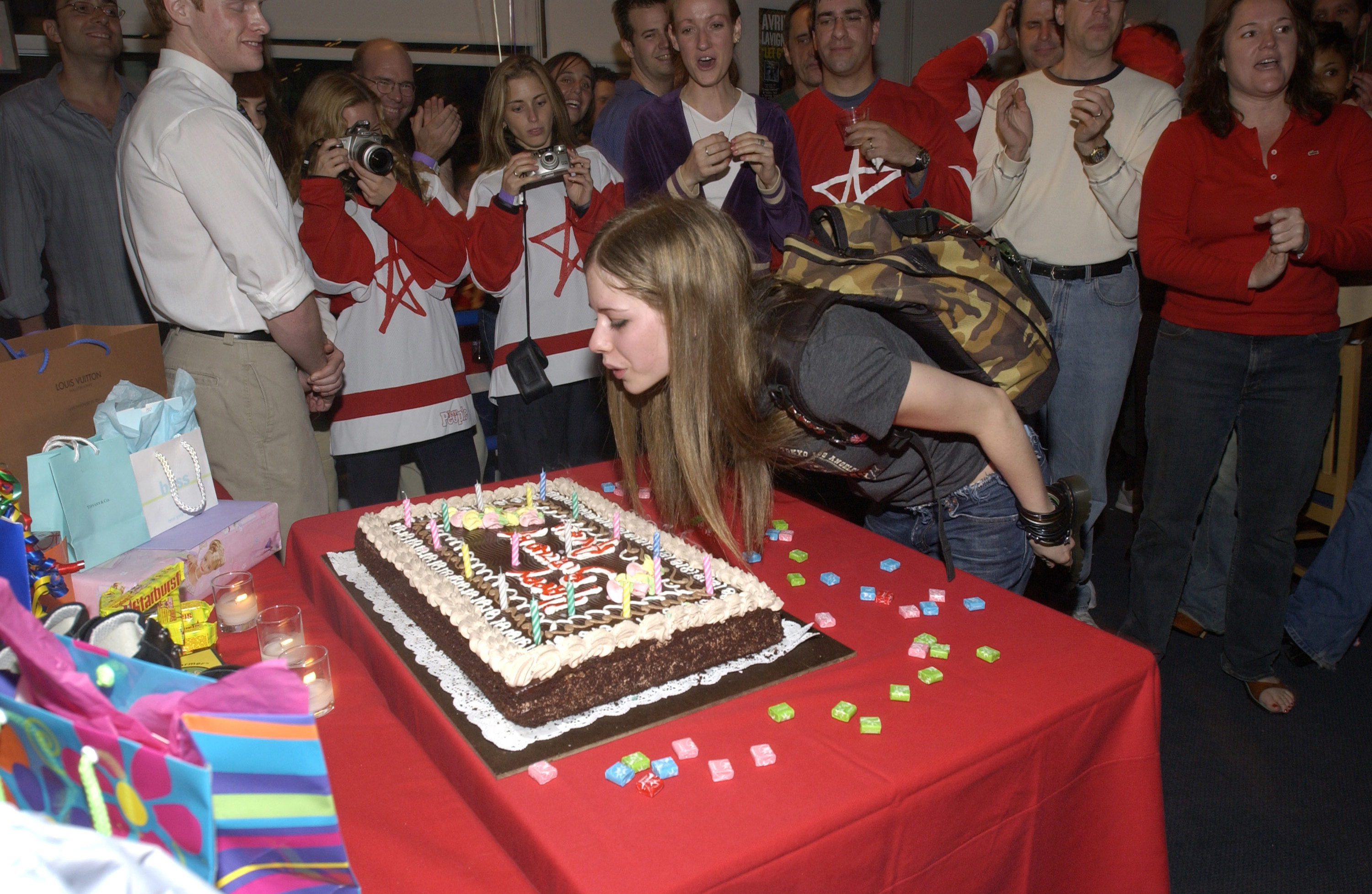 Avril Lavigne blows out her birthday cake candles surrounded by fans taking pictures