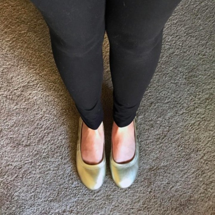 person wearing a pair of gold flats and black jeans