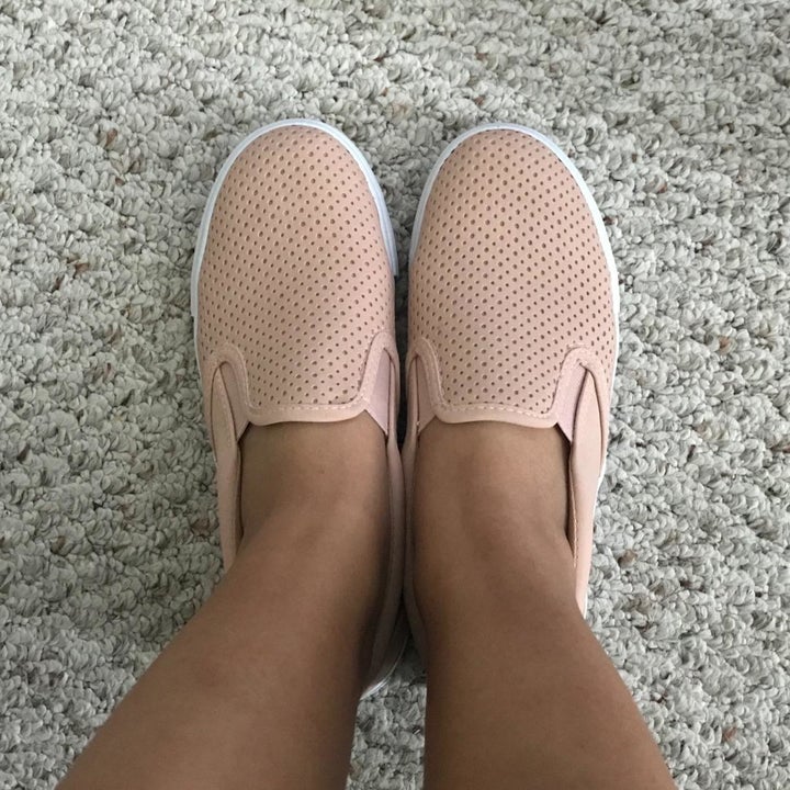 a reviewer photo of someone wearing the slip-on sneakers in pink 