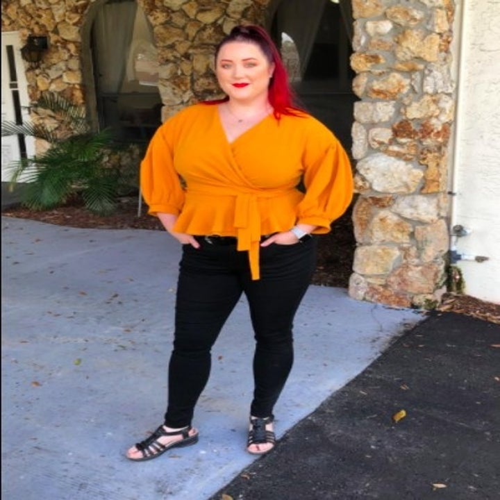 person wearing a pair of black skinny jeans and a orange blouse