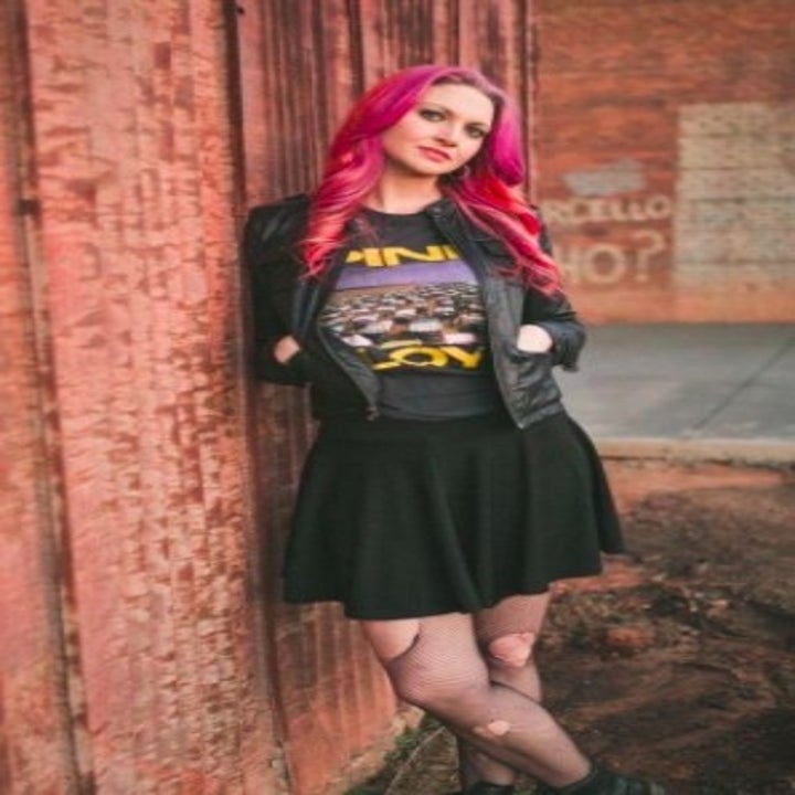 person wearing a black skirt with a black graphic t shirt and a leather jacket