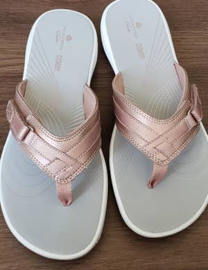 a reviewer photo of a pair of flip-flops with rose gold straps 