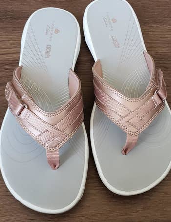 a reviewer photo of a pair of flip-flops with rose gold straps 