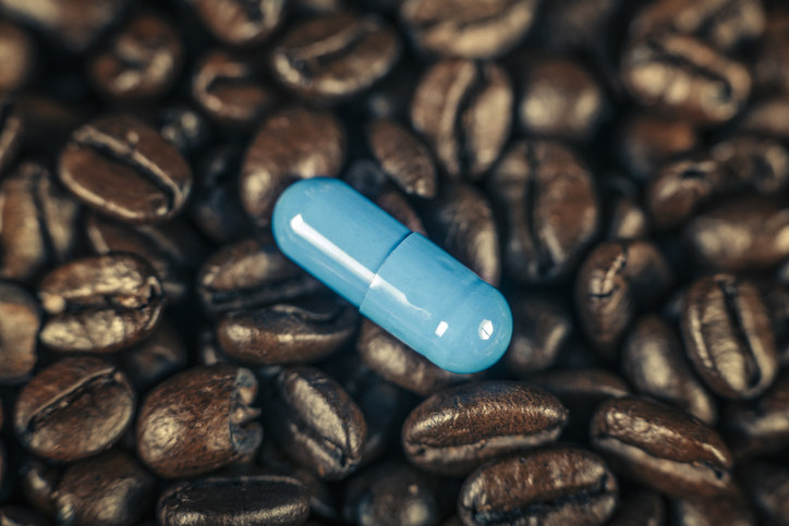 A pill sitting on top of a pile of coffee beans