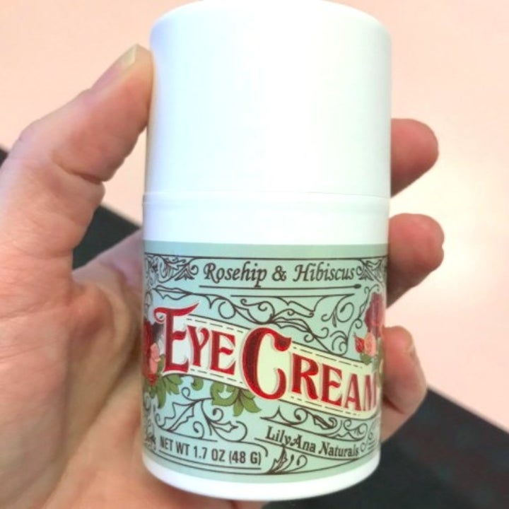 person holding up a bottle of eye cream