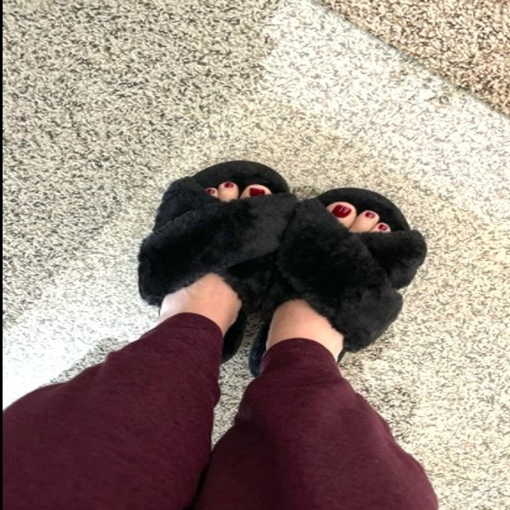 person wearing a pair of fuzzy black slippers