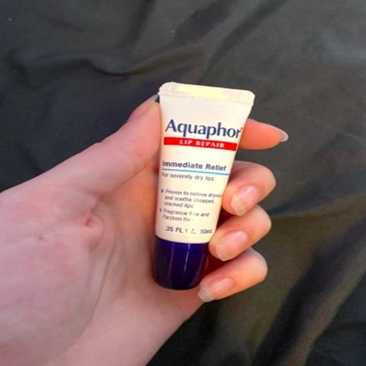 person holding up a aquaphor tube of ointment