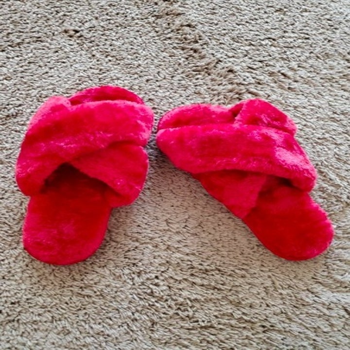 a pair of pink fuzzy slippers on carpet
