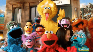 The full Sesame Street crew smiling and waving at the camera 