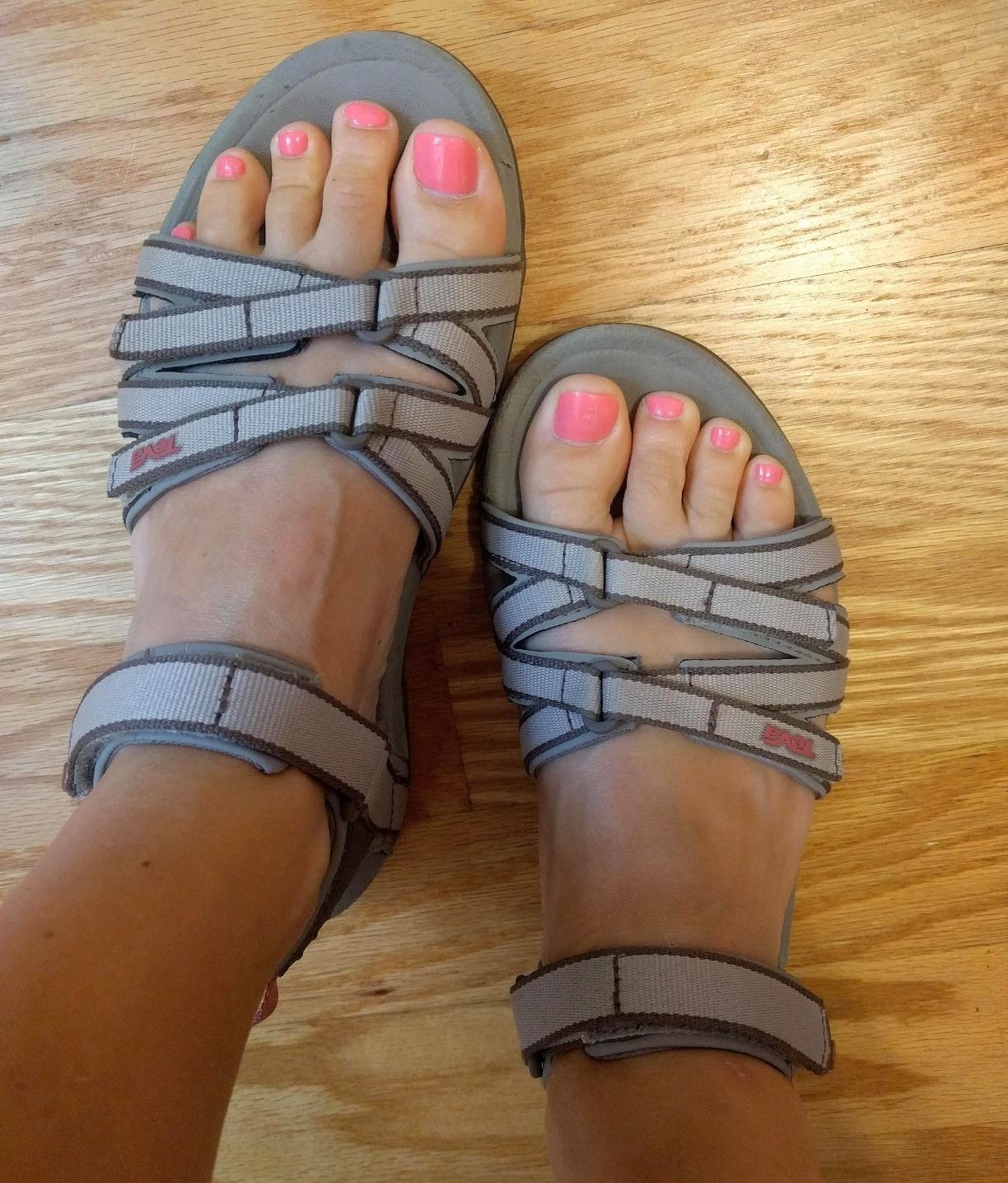 a reviewer photo of a pair of feet wearing gray Teva sandals 