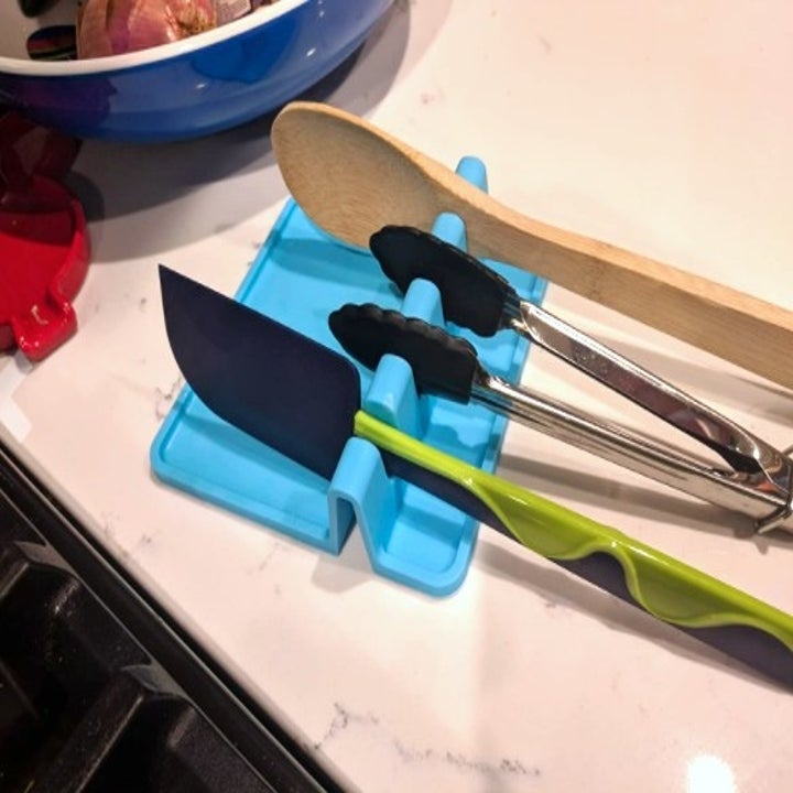 a bright blue spoon rest with three utensils resting on it