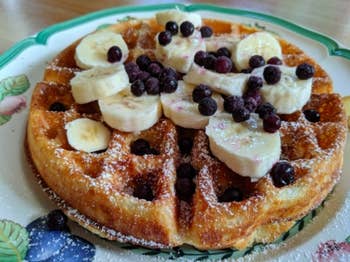 reviewer photo of a waffle with powdered sugar, bananas, and berries on top