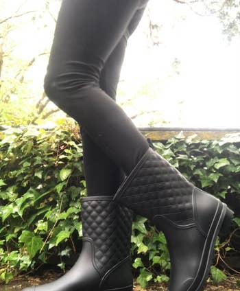 a reviewer photo of someone wearing black leggings and the rainboots outside 