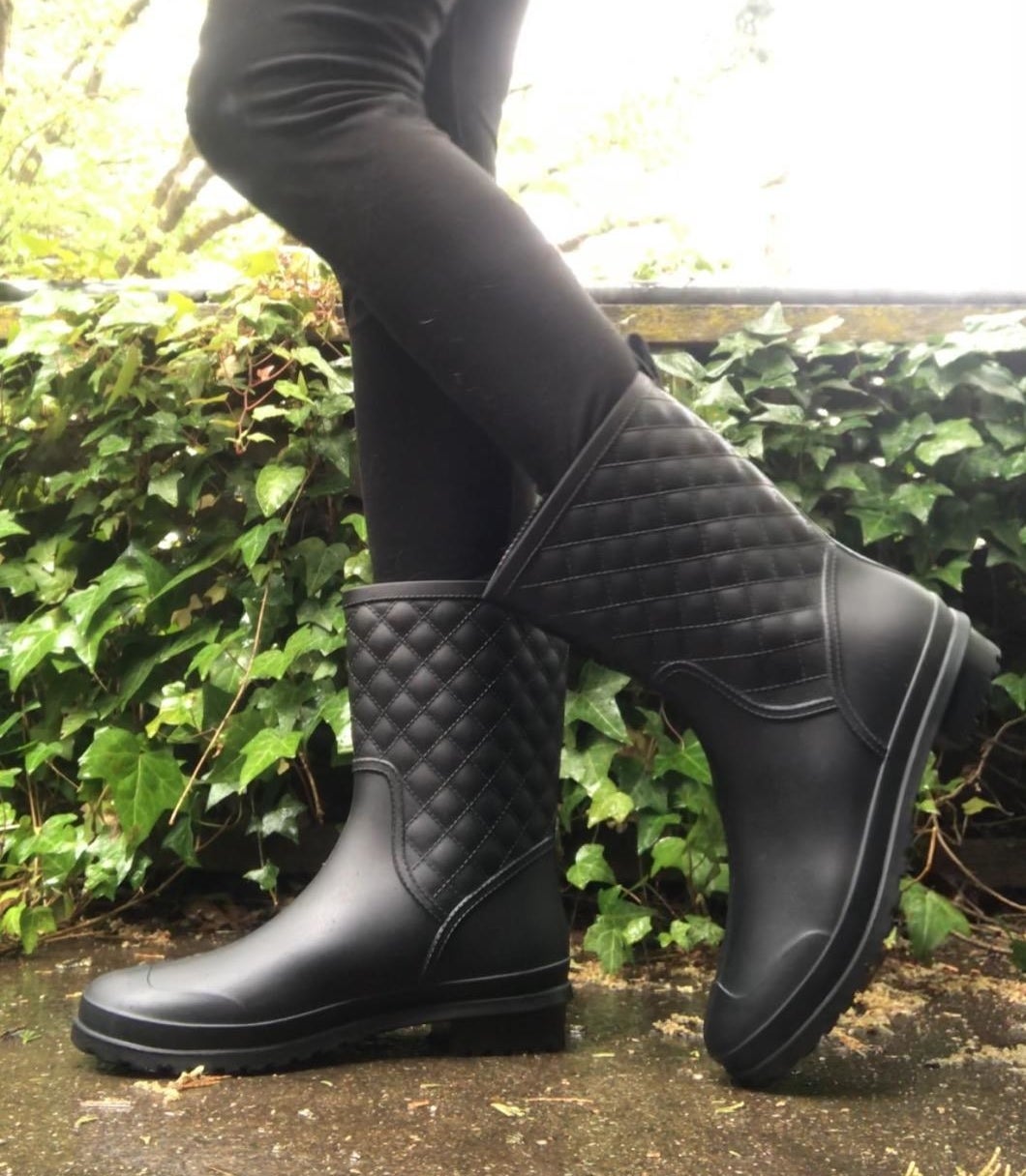 a reviewer photo of someone wearing black leggings and the rainboots outside 