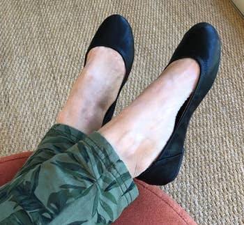 a reviewer photo of a pair of feet wearing green pants and black ballet flats 