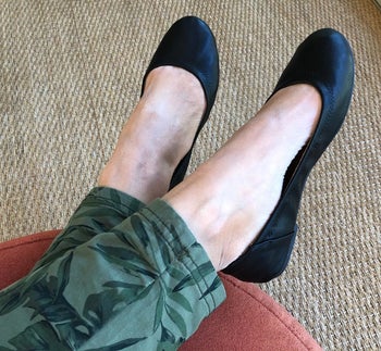 a reviewer photo of a pair of feet wearing green pants and black ballet flats 