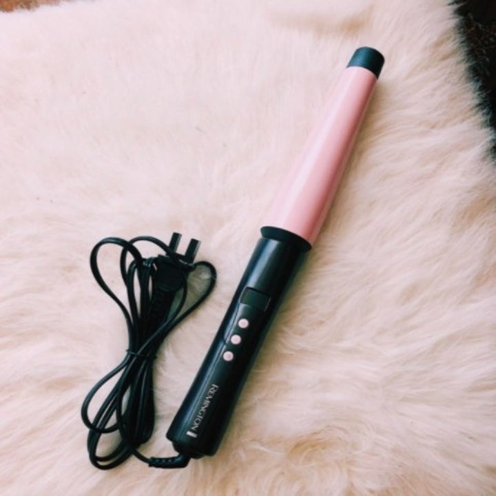 a pink remington curling want on a faux fur surface