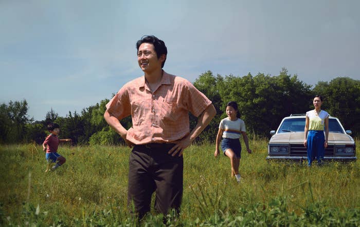 Steven Yeun&#x27;s character stands in a field while his family plays around him.
