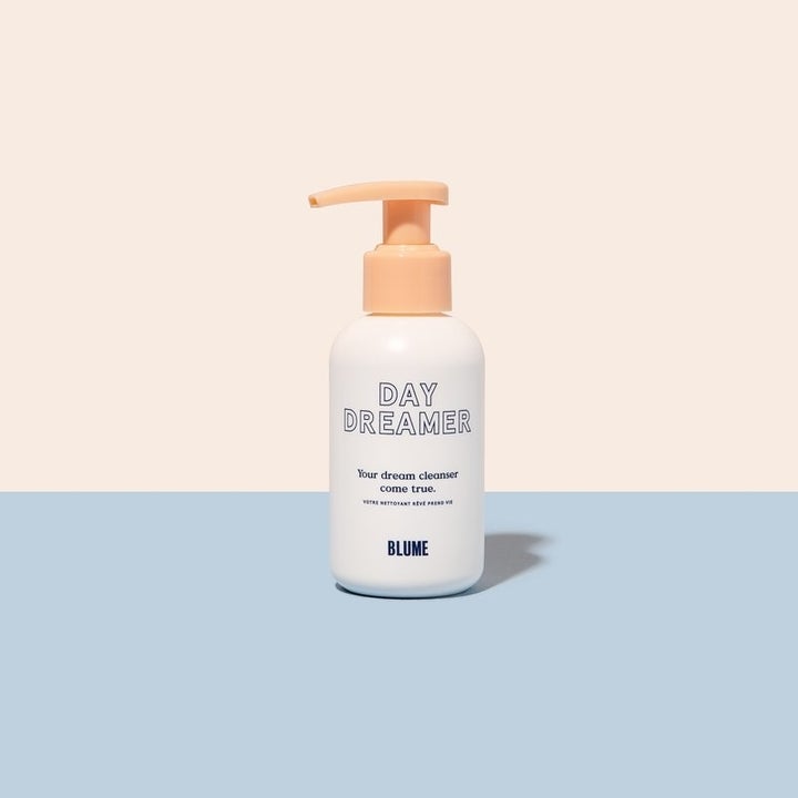 a white bottle that says "day dreamer" on it with an orange pump lid