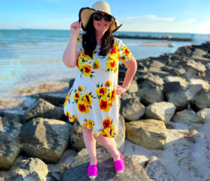 Reviewer wearing the white and yellow sundress with sunflower pattern