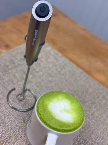 gray milk frother next to a frothy matcha latte