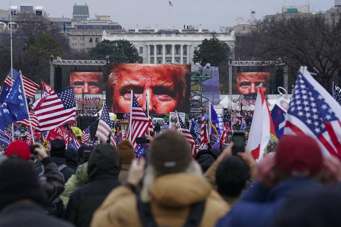 A close-up of Trump's eyes appear on three screens in the background before a crowd of people waving US and Trump flags