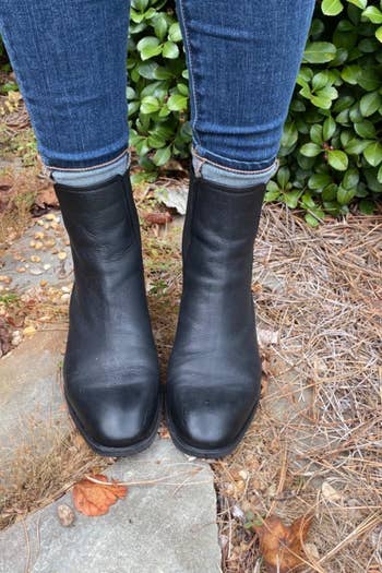 a reviewer photo of someone outside wearing jeans and the black ankle boots 