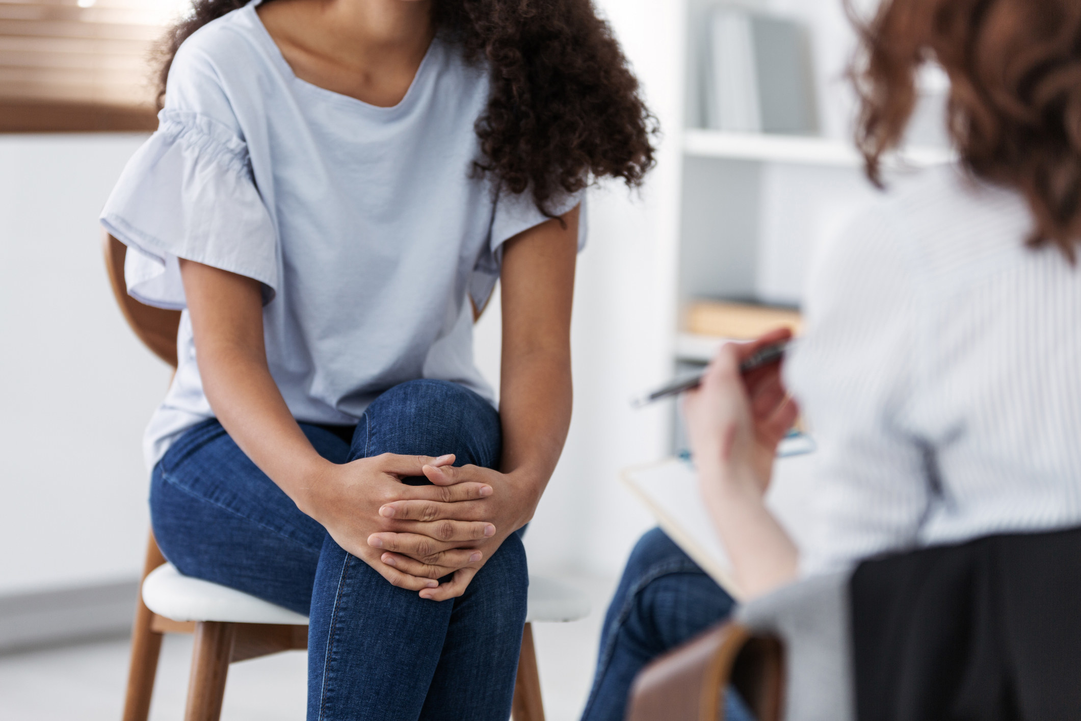 Someone sits across a therapist during a therapy session