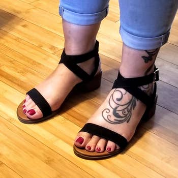 A reviewer photo of someone wearing jeans and the strappy block heel sandals in black 