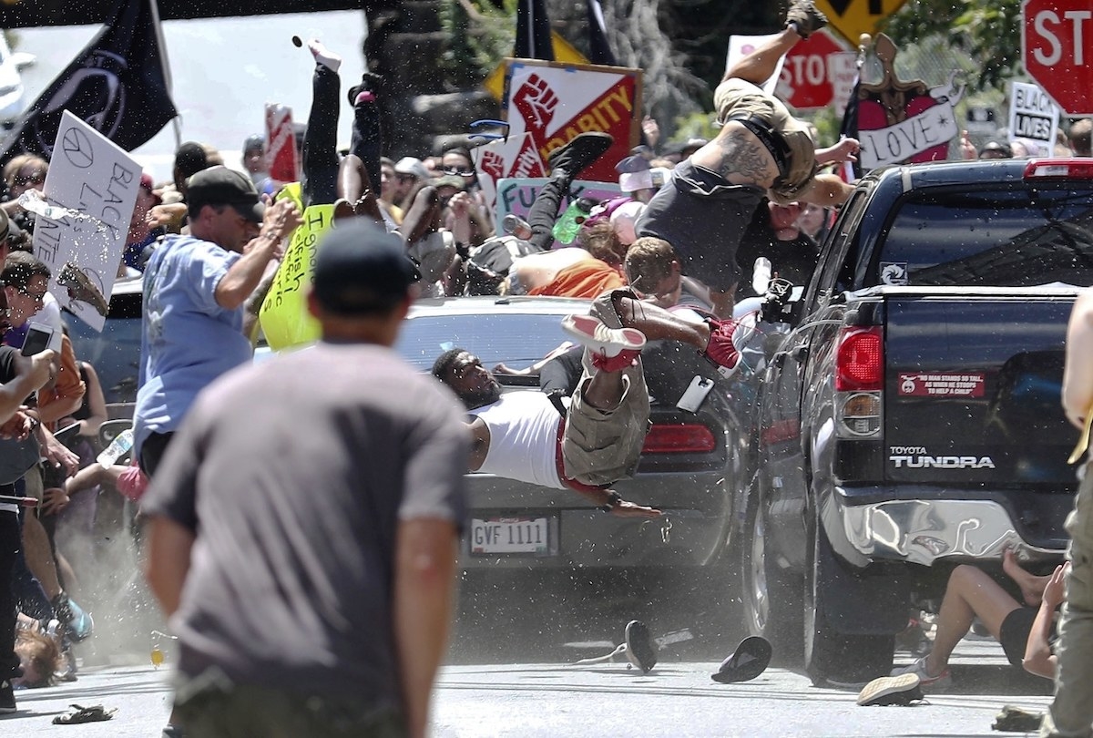 A car drives into a crowd of protesters waving signs as bodies tumble off it