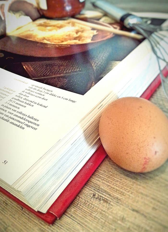 A cookbook and an egg resting next to it.
