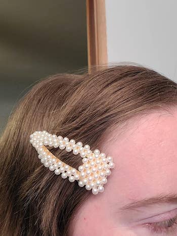 reviewer wears a chunky pearl barrette in their hair
