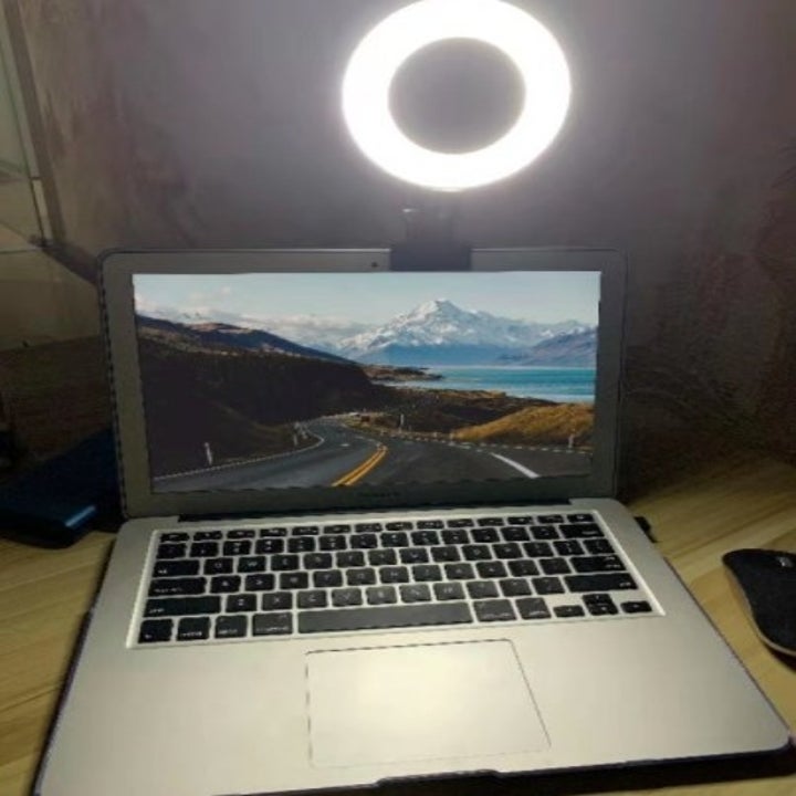 a laptop computer with a clip on LED ring light at the top