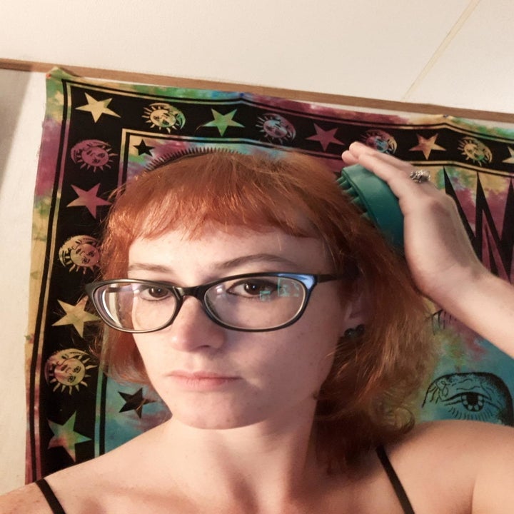 reviewer holds green scalp massager against their hair