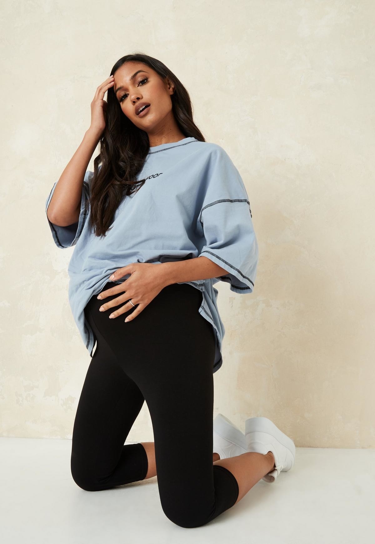 a pregnant model kneeling in black high-waisted leggings