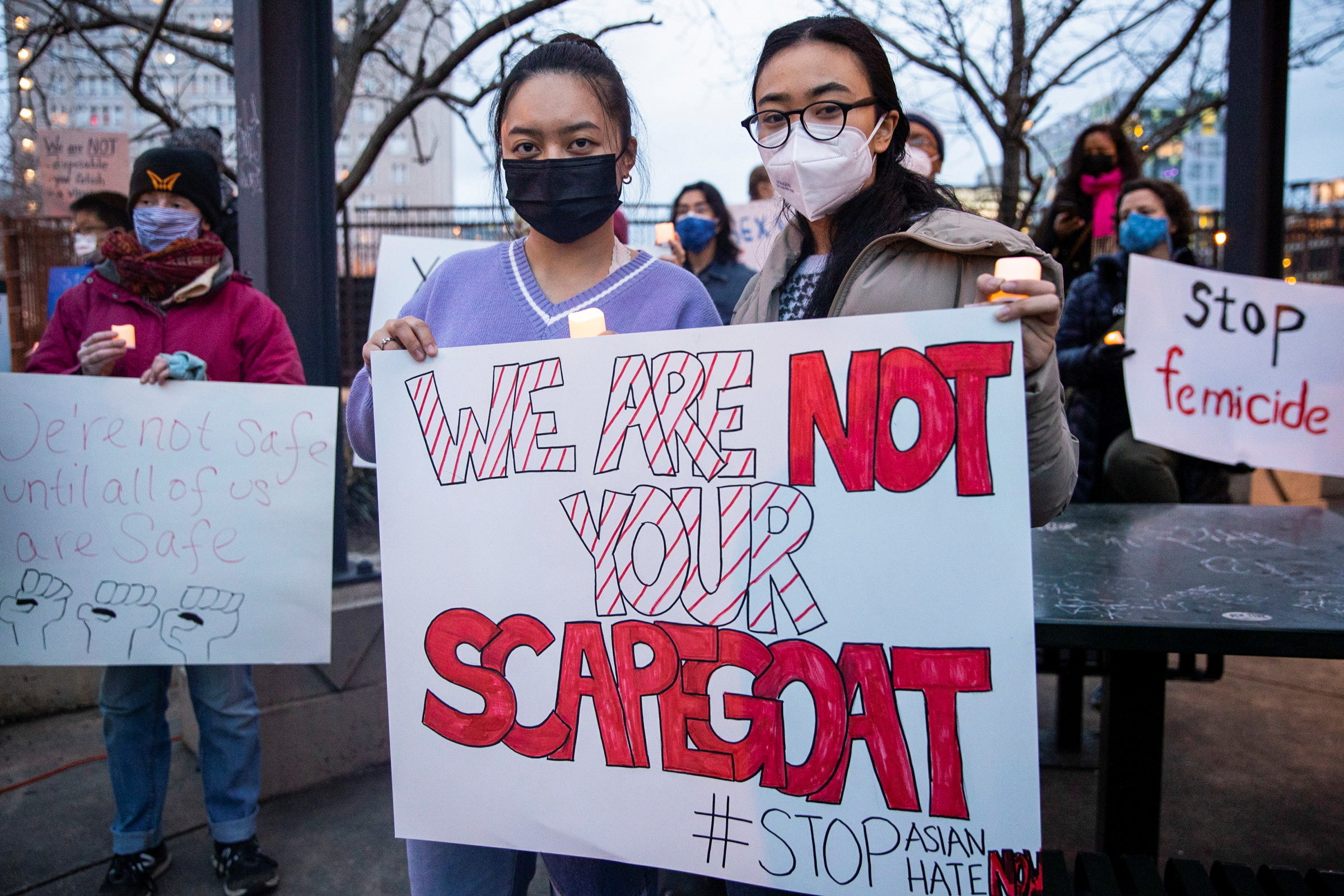 Two women hold a sign reading &quot;We are not your scapegoat&quot;